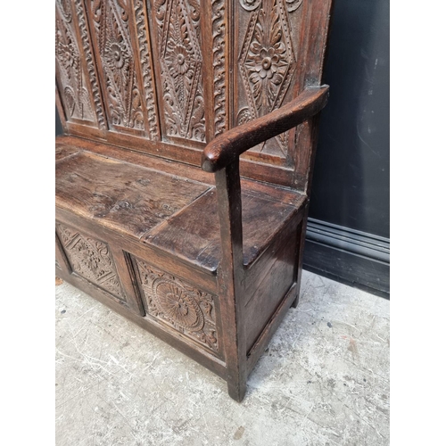 1286 - A late 17th century carved oak panelled box seat settle, 106cm wide.