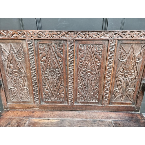 1286 - A late 17th century carved oak panelled box seat settle, 106cm wide.