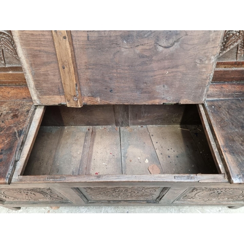 1286 - A late 17th century carved oak panelled box seat settle, 106cm wide.