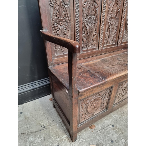 1286 - A late 17th century carved oak panelled box seat settle, 106cm wide.