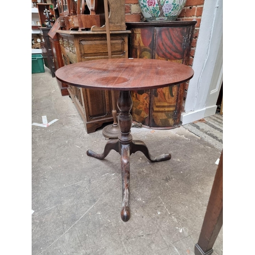 1227 - A George III mahogany circular tilt top tripod table, (restorations), 69cm diameter.... 