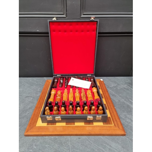 1333 - A carved wood chess set, king 13.7cm, pawn 8.4cm, cased; together with chequerboard, 50cm wide.... 