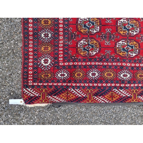 1757 - A small Bokhara rug, having repeated decoration, on red ground, 198 x 124cm.