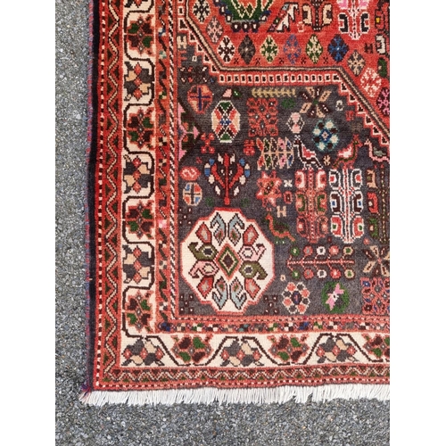 1766 - A large Persian carpet, central field decorated with geometric shapes and flowers, with floral borde... 