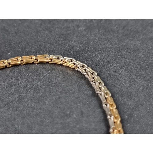 1003 - A two tone yellow metal watch chain, clasp stamped '18', 34cm long.