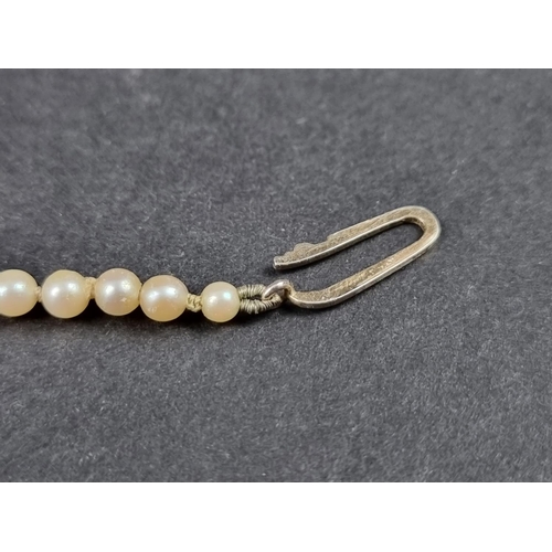 1053 - A graduated pearl necklace, the clasp stamped '9ct', 53cm long; together with a stick pin, having pe... 