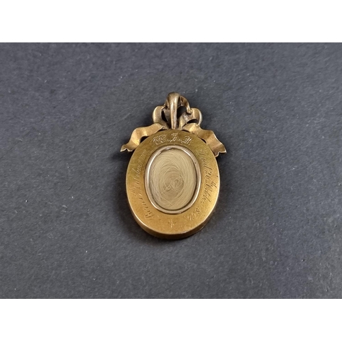 1064 - A Victorian yellow metal mourning pendant, having ribbon shaped diamond and black enamel surmount, w... 