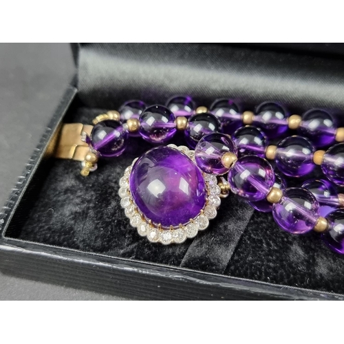 1067 - A modern amethyst and yellow metal strand necklace, the clasp set cabochon amethyst surrounded by a ... 