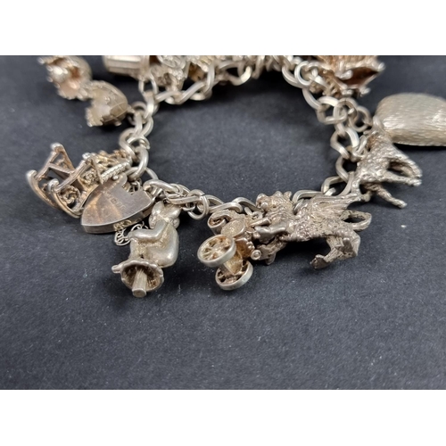 1070 - A white metal charm bracelet, having hallmarked padlock clasp and fourteen attached charms; together... 