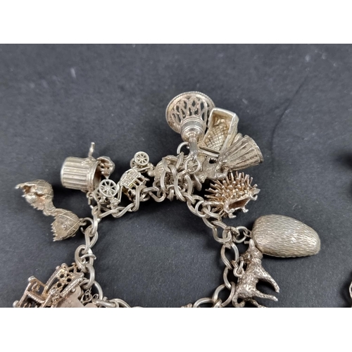 1070 - A white metal charm bracelet, having hallmarked padlock clasp and fourteen attached charms; together... 