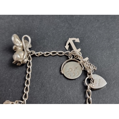 1070 - A white metal charm bracelet, having hallmarked padlock clasp and fourteen attached charms; together... 