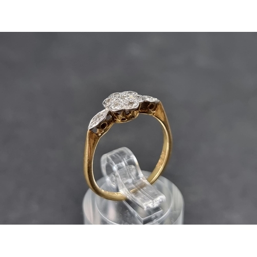 914 - An 18ct gold daisy ring, set seven small diamonds with a further diamond to each shoulder, size M, g... 