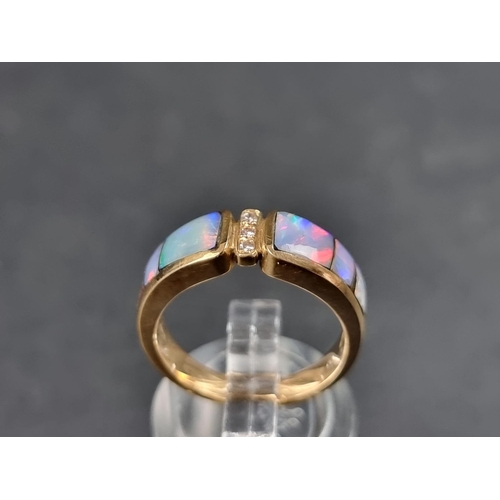 931 - A modern yellow metal ring, set three graduated opal panels with three small brilliant cut diamonds ... 