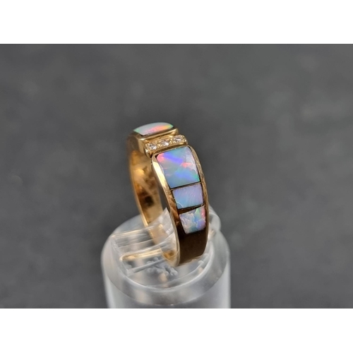 931 - A modern yellow metal ring, set three graduated opal panels with three small brilliant cut diamonds ... 