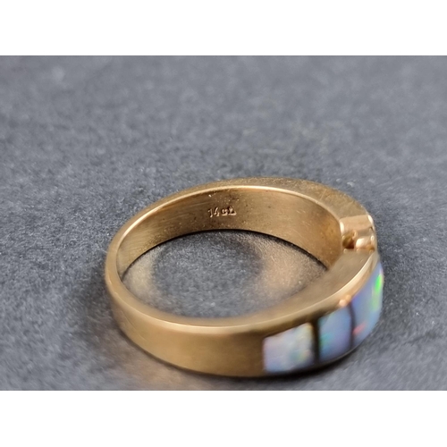 931 - A modern yellow metal ring, set three graduated opal panels with three small brilliant cut diamonds ... 