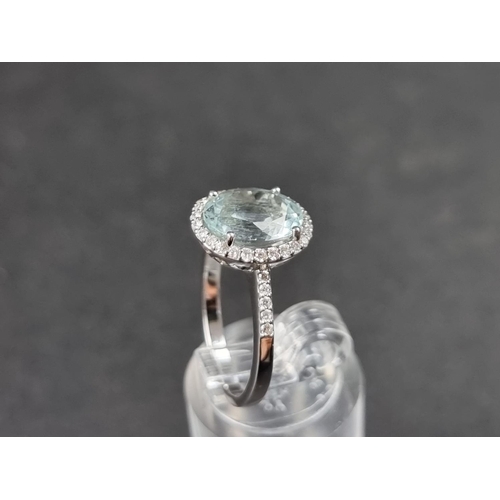 932 - A white metal ring, set central faceted aquamarine of approx. 2.60ct, surrounded by small brilliant ... 