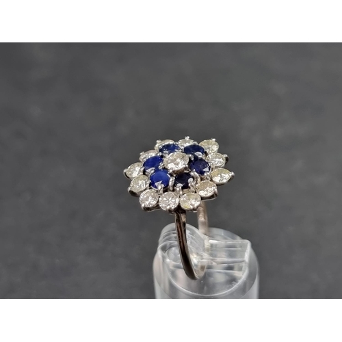 937 - A diamond and sapphire floral cluster ring, set central brilliant cut diamond surrounded by a row of... 