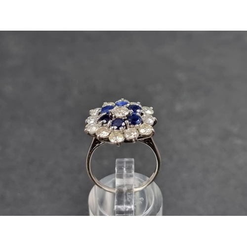 937 - A diamond and sapphire floral cluster ring, set central brilliant cut diamond surrounded by a row of... 