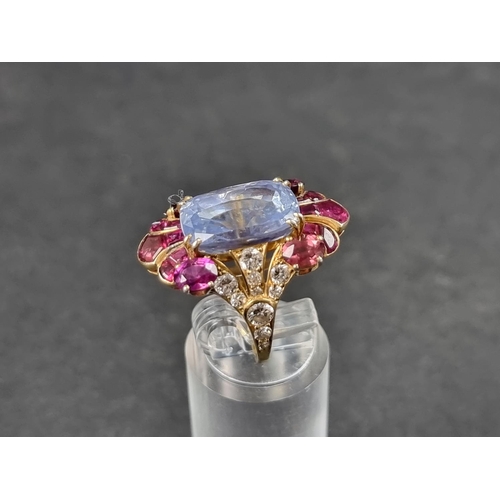 941 - A yellow metal cocktail ring, set central blue topaz surrounded by rubies and diamonds, size K 1/2.... 