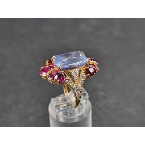 941 - A yellow metal cocktail ring, set central blue topaz surrounded by rubies and diamonds, size K 1/2.... 