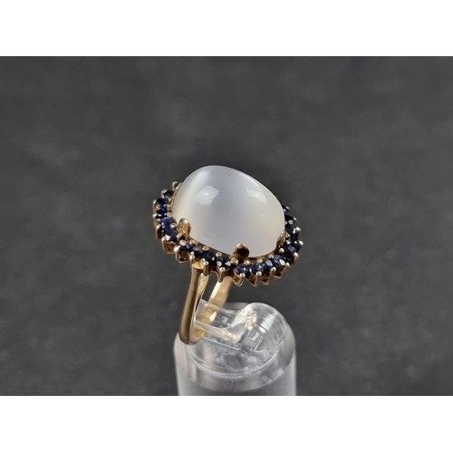 943 - A yellow metal moonstone and sapphire cluster ring, size O.