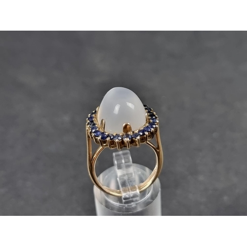 943 - A yellow metal moonstone and sapphire cluster ring, size O.