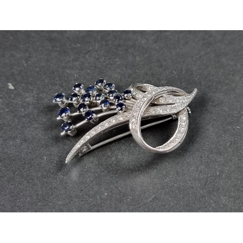 949 - A sapphire and diamond floral and scroll brooch, stamped 750, set seventeen sapphires and forty eigh... 