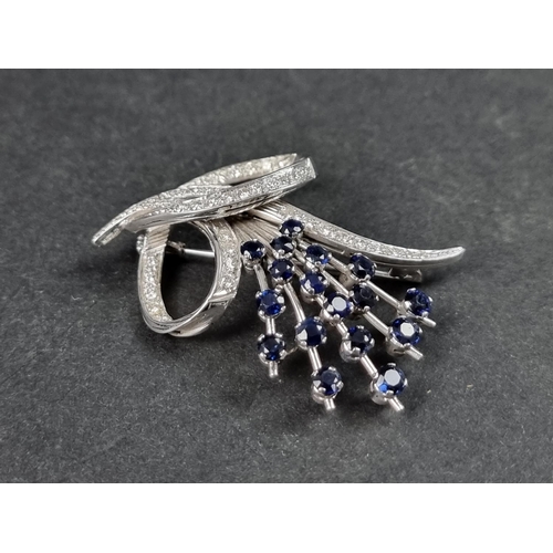 949 - A sapphire and diamond floral and scroll brooch, stamped 750, set seventeen sapphires and forty eigh... 