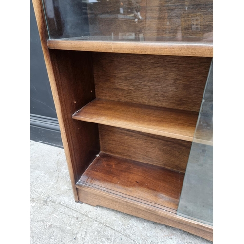 1012 - A mahogany bookcase, with glass sliding doors, 91.5cm wide, labelled Herbert E Gibbs.... 