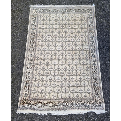 1145 - A Kashmiri rug, having repeated decoration to central field, geometric borders on a cream and black ... 