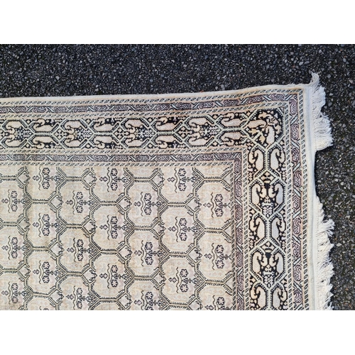 1145 - A Kashmiri rug, having repeated decoration to central field, geometric borders on a cream and black ... 