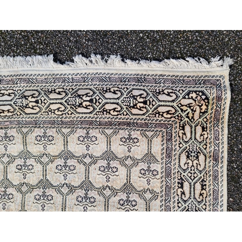 1145 - A Kashmiri rug, having repeated decoration to central field, geometric borders on a cream and black ... 