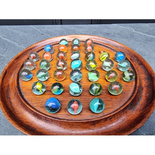 1317 - A mahogany solitaire board and thirty six glass marbles, 22cm diameter.  