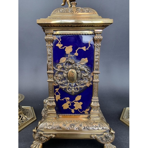 1383 - An impressive Victorian brass and porcelain clock garniture, the panels by Taylor, Tunnicliff & ... 