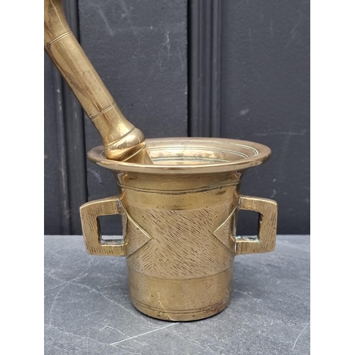 1440 - An antique brass twin handle mortar, 10.5cm high; together with similar pestle, 22cm long. (2)... 