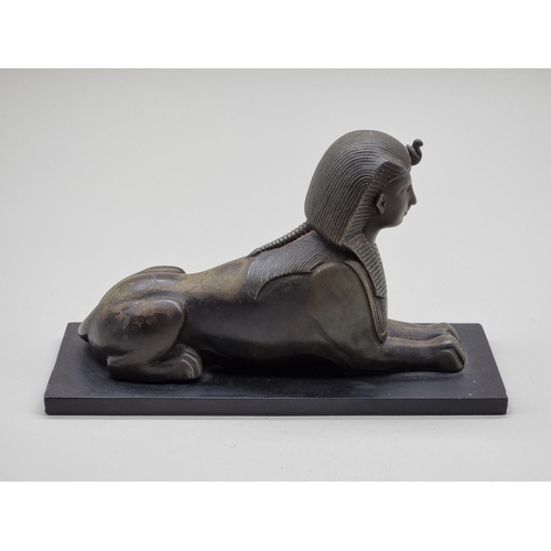 1583 - A bronze sphynx, on slate base, 28cm long.