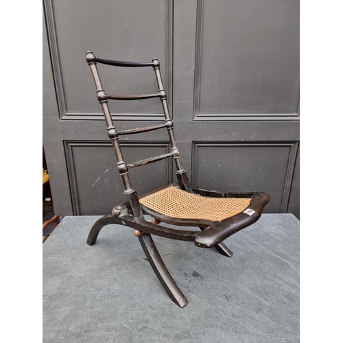 1089 - A Victorian ebonized and cane folding campaign style chair. 