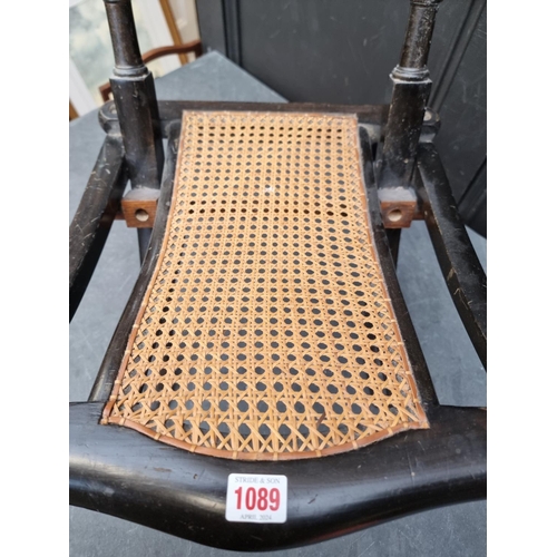 1089 - A Victorian ebonized and cane folding campaign style chair. 