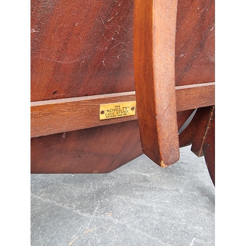 1173 - An Edwardian mahogany and inlaid folding cake stand, labelled 'The Novelty'.