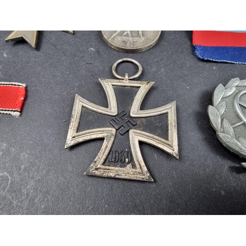 220 - A WWII German Iron cross; together with seven other German WWII medals and badges.