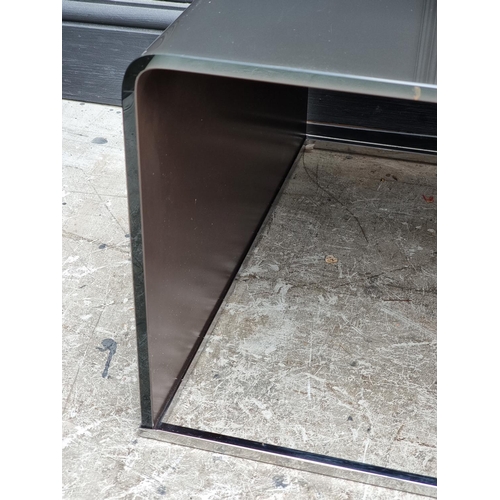 1122 - Two Italian smoked glass and chrome occasional tables, 109cm wide. (2)