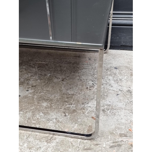 1122 - Two Italian smoked glass and chrome occasional tables, 109cm wide. (2)