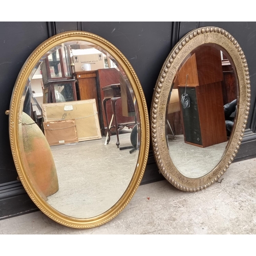 1130 - A plated metal framed oval wall mirror, 65 x 90cm; together with another similar gilt framed ex... 