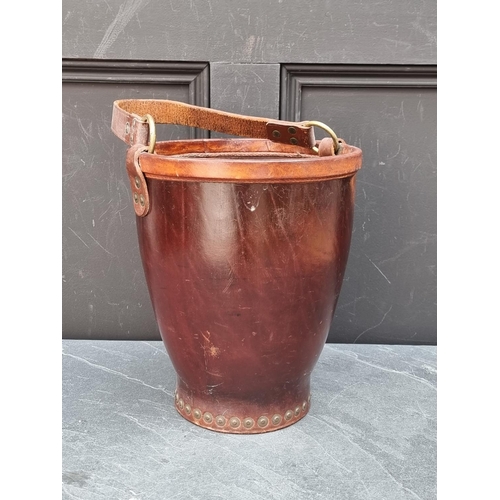 1151 - A tan leather and brass studded swing handled bucket, stamped 'Made in England', the bucket 30.5cm h... 