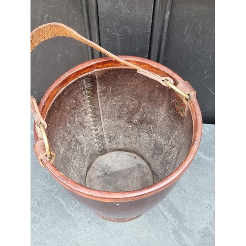 1151 - A tan leather and brass studded swing handled bucket, stamped 'Made in England', the bucket 30.5cm h... 