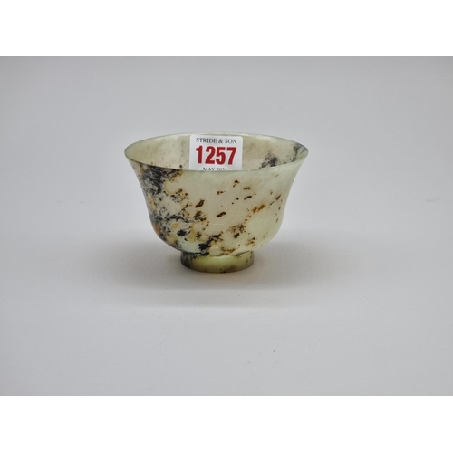 1257 - A Chinese mottled green jade bowl, 9.8cm diameter.