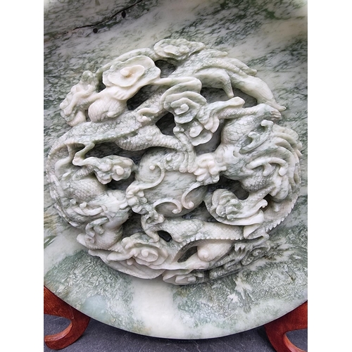 1550 - A large pair of Chinese carved mottled green jade relief chargers, decorated with dragons, 35cm diam... 