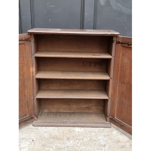 1002 - An 18th century oak panelled mural cupboard, with pierced geometric decoration to the doors, 85... 