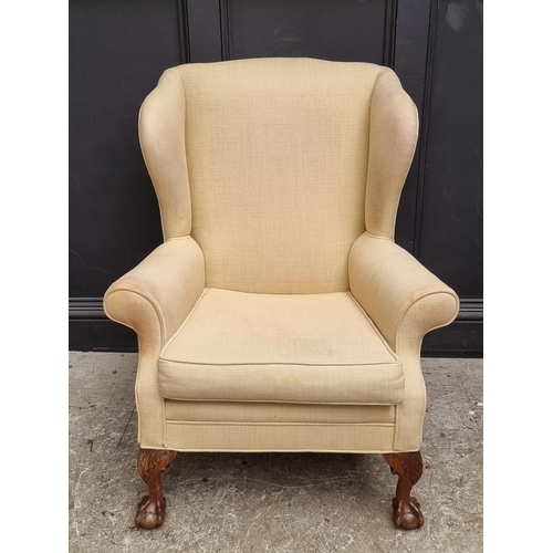 1085 - A wing armchair, on walnut ball and claw legs to the front.