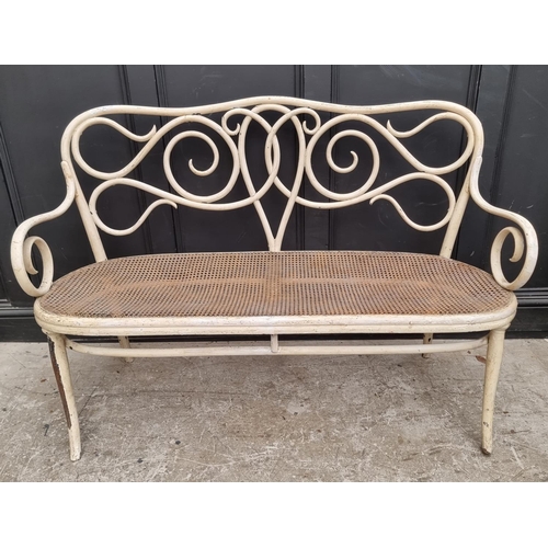 1113 - A late 19th century bentwood and cane settee, in the manner of Thonet, 143cm wide.... 